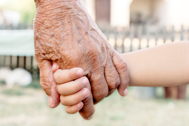 Grandchild holding grandparent for the hand,selective focus