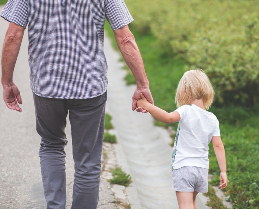 A grandfather holding hands with his granddaughter while walking down the street in Tampa, Florida.